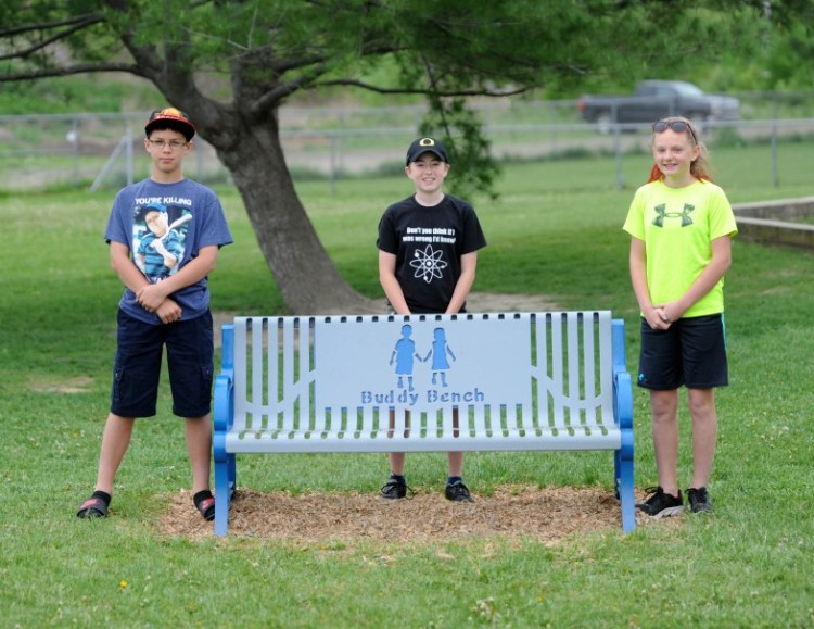 Benton Elementary School sixth-grade Student Council officers, from left, Andrew Trombley, 12, Corbin Kissinger, 12, and Taylor Wilkie, 12, pose for a portrait Friday in front of a buddy bench on the playground at Benton Elementary School. Students who are new to the school or feel lonely can sit on the bench, and other students will join them.