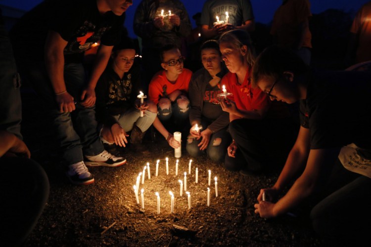 Jacob Hoagland, right, places candles into the ground to form a G during the Pike County Vigil at the Pike County  Fairgrounds in Piketon, Ohio on Friday.