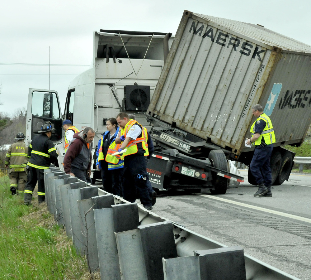 Driver Paul Cusano is checked by medical personnel as state police investigate after Cusano's tractor-trailer jackknifed on Interstate 95 in Waterville on Thursday.