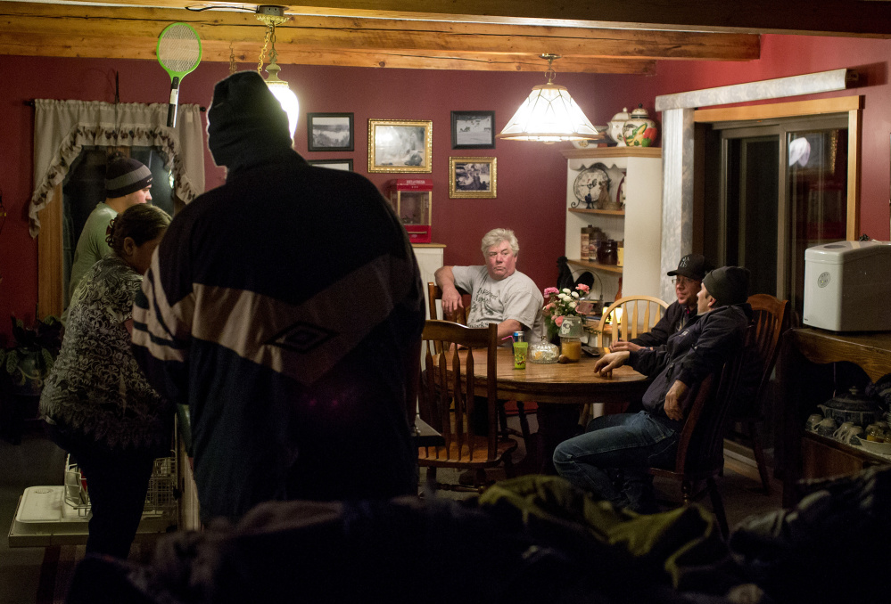 Carter McBreairty, center, listens to the conversation of friends and family around the dinner table of his home in Allagash, an Aroostook County town consisting of a dispersed collection of homes, hunting lodges and small businesses. Allagash is surrounded by industrial forests that stretch to the borders of Quebec, Canada, and Baxter State Park, 60 miles south.