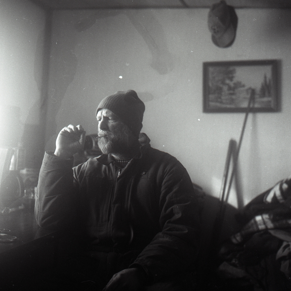 Jess McBreairty, the subject of an undercover sting by Maine Game Wardens, smokes a hand rolled cigarette as he wakes up in his trailer in Allagash Sunday, February 14, 2016. McBreairty lives in poverty, eating many meals at friends' homes just to get by. This was photographed with black and white film on a Rolleiflex camera.