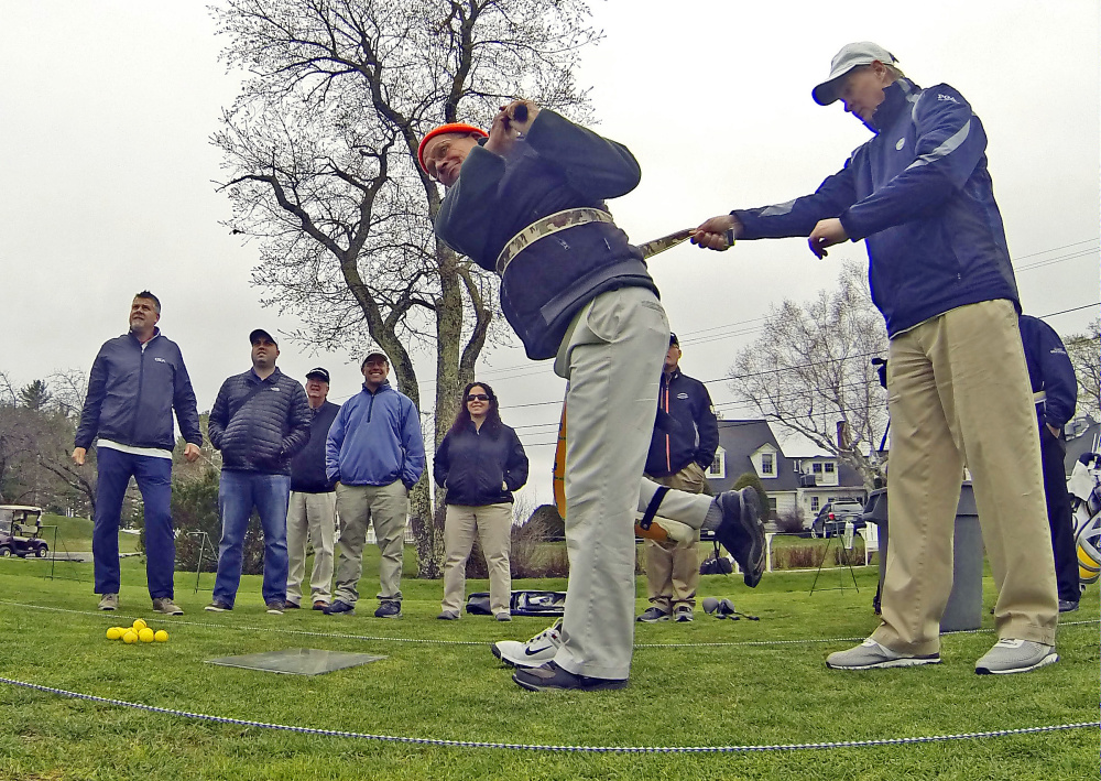 Rockland Golf Club assistant pro Bob Mathews, left, takes a swing while wearing a prosthetic leg as Samoset Resort director of golf Gary Soule assists by holding onto a balance belt during training on how to teach adaptive golf Thursday at the Augusta Country Club in Manchester.
