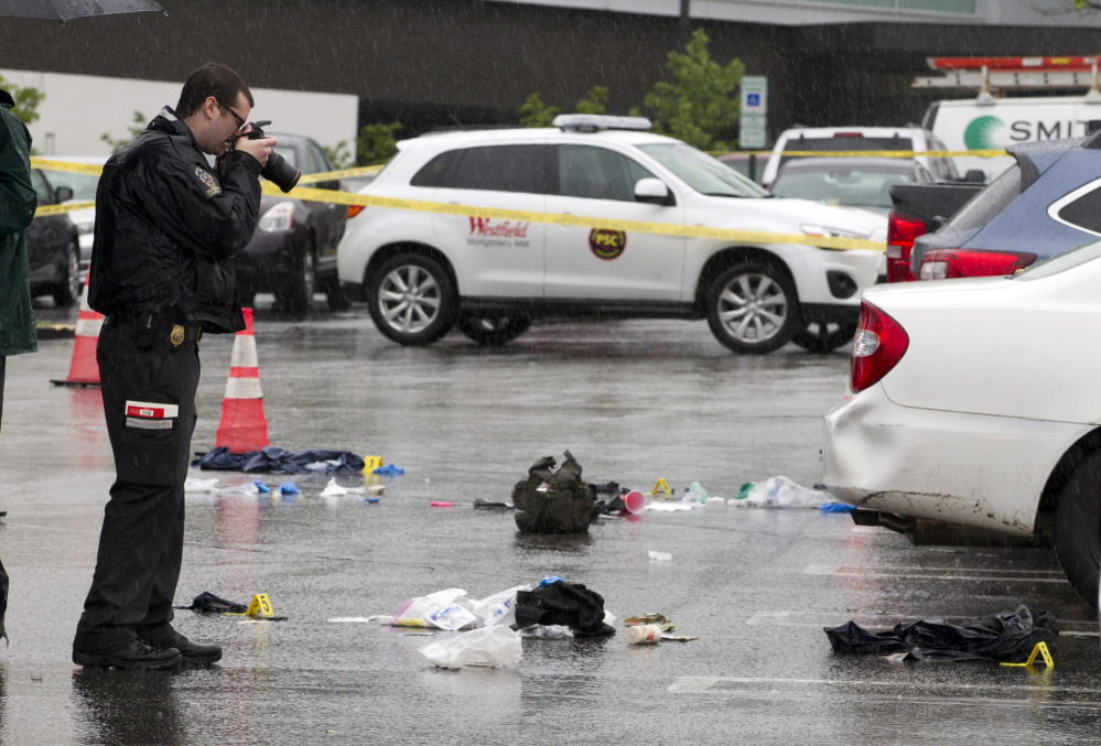 A Montgomery County police officer takes pictures of evidence after a shooting at Westfield Montgomery Mall parking lot in Maryland on Friday.
