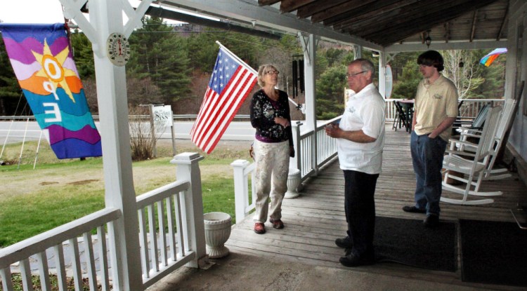 Sterling Inn owner Eric Angevine, center, speaks with house painter Lou Kifer on the porch of the inn in Caratunk recently. Angevine's son, Zachary, is at right.