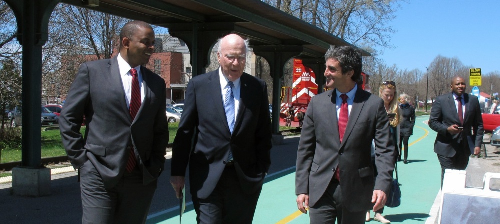 U.S. Transportation Secretary Anthony Foxx, left, Sen. Patrick Leahy, center, and Burlington, Vt., Mayor Miro Weinberger walk outside a rail station in Burlington as they announce Amtrak trains will come back to Vermont's largest city.