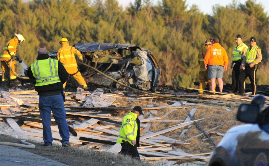 Police and firefighters work on March 18 at the scene of the multi-vehicle crash on Route 17 in Washington. A truck driver has been arrested in Virginia and charged in connection with the crash, which killed two people.