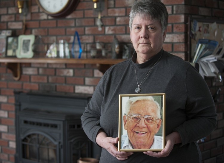 Kathy Day stands with a portrait of her father, John P. McCleary Sr., in her Bangor home Wednesday. McCleary died of a preventable hospital-acquired infection in 2009.
