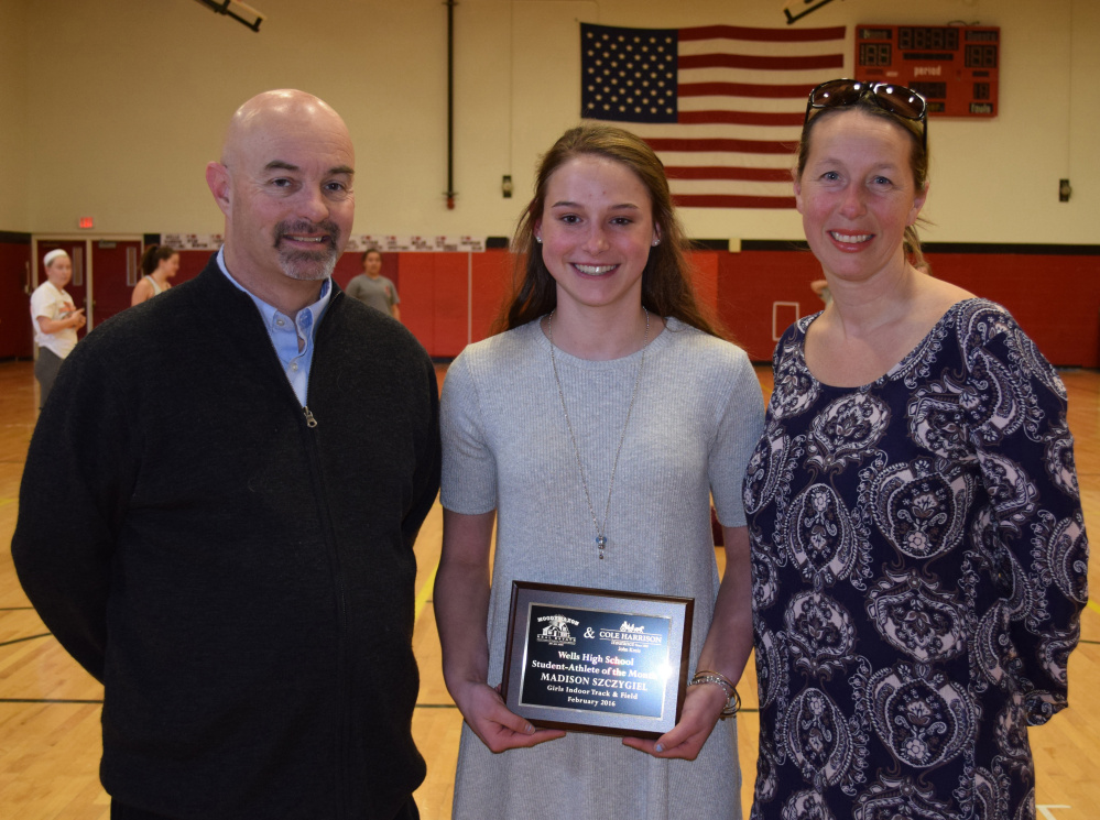 Madison Szczygiel, center, a sophomore at Wells High School, receives a plaque honoring her as Student Athlete of the Month from Jack Molloy, student activities director, and Pamela Moody-Maxon, right, of MoodyMaxon Real Estate.