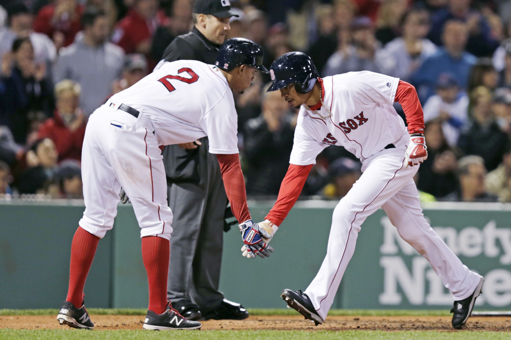 Mookie Betts low-fives Xander Bogaerts after scoring on a single by Dustin Pedroia during Boston's six-run rally in the fourth inning.
