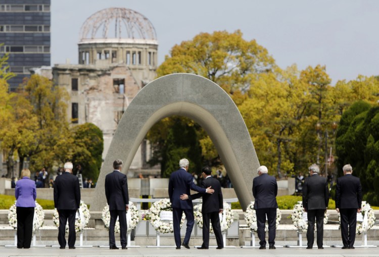 U.S. Secretary of State John Kerry (center L) puts his arm around Japan's Foreign Minister Fumio Kishida (center R) after they and fellow G7 foreign ministers laid wreaths at the cenotaph at Hiroshima Peace Memorial Park and Museum in Hiroshima, Japan April 11, 2016.