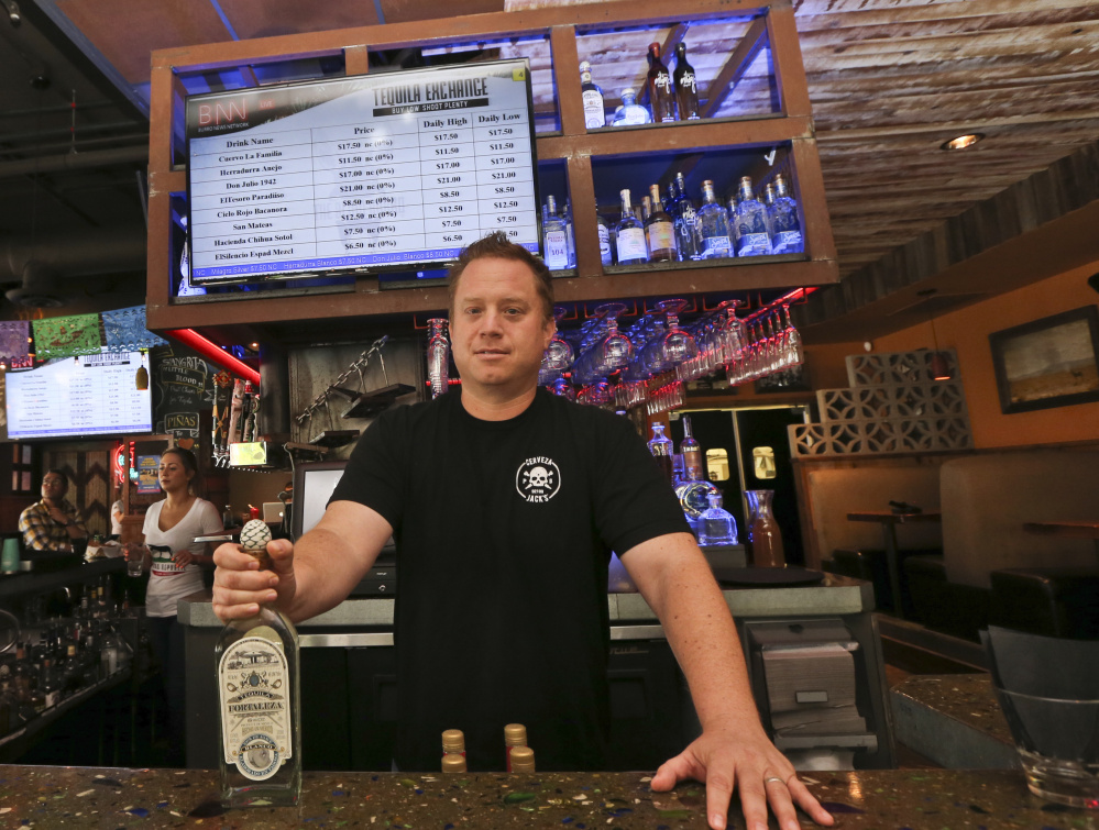 Frank Miller offers tequila at The Blind Burro in San Diego, where prices of shots can change every five minutes.