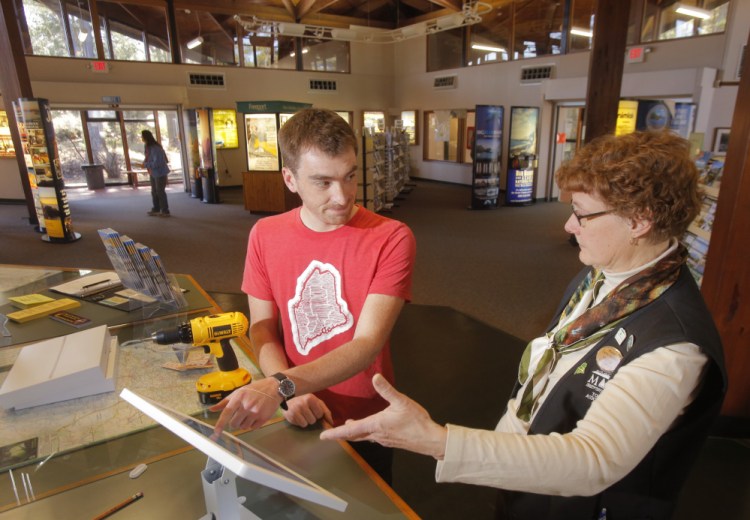 Nate Wildes explains the Live + Work in Maine iPad to Marcia Peverly, manager of the visitors' center in Kittery, where the kiosk gives the program exposure to many of the 34 million people who visit the state each year.