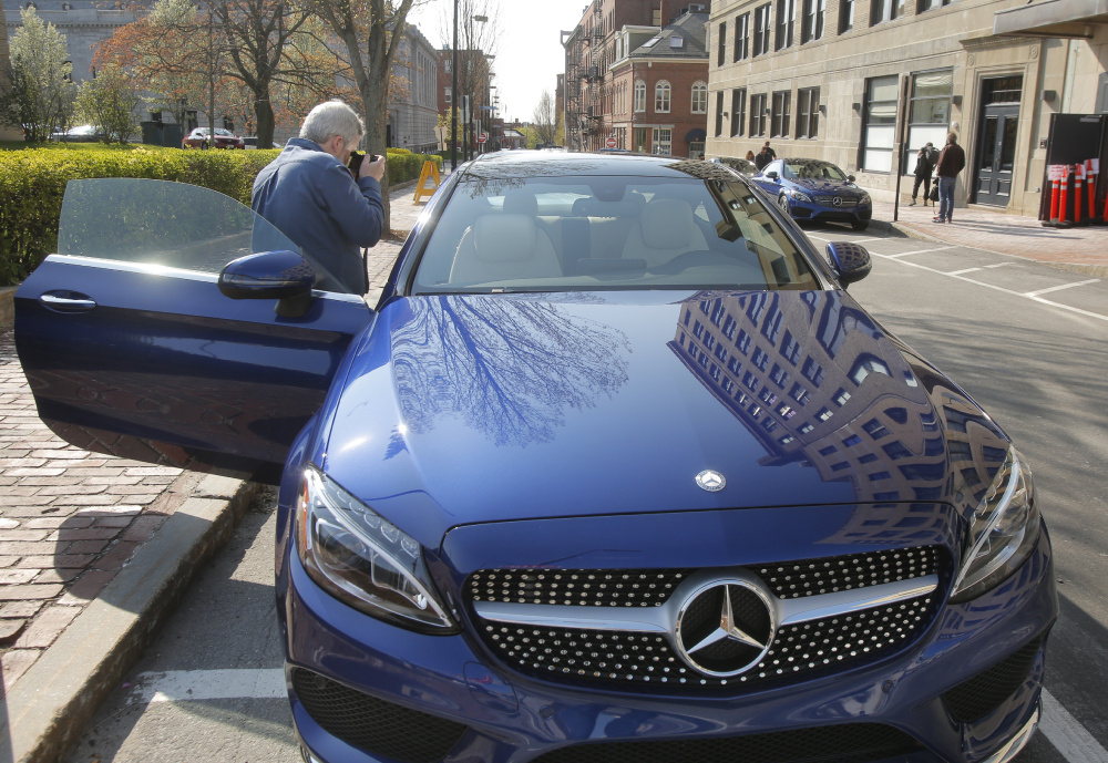 Perry Stern, editor-in-chief of Automotive Content Experience, a website that reviews automobiles and covers the auto industry, takes photos of the interior of a Mercedes C300 coupe on Market Street in Portland on Thursday.