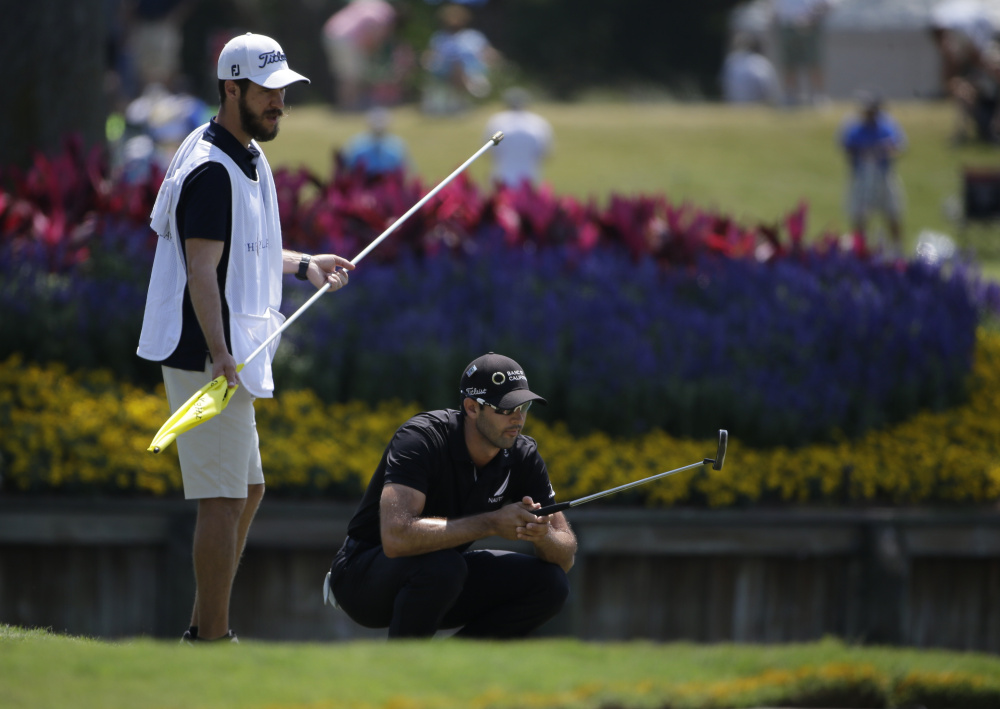 Cameron Tringale and his caddie, Carl Smith, look at Tringale's shot on the 17th green during the first round of The Players Championship in Ponte Vedra Beach, Fla., on Thursday. Tringale was one of five players two strokes back at 7-under 65 after an unusually forgiving day at TPC Sawgrass.