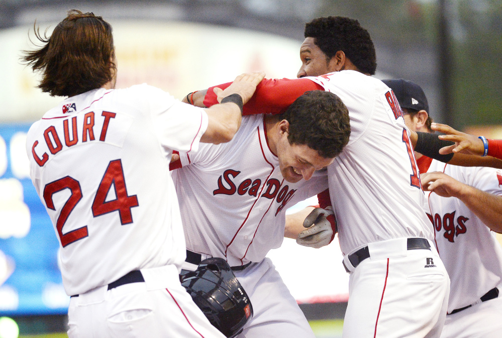 Nate Freiman, center, is swarmed by teammates after hitting a walk-off single for the Portland Sea Dogs in the opener of a doubleheader Friday night against the Binghamton Mets. The Sea Dogs won the opener 1-0.