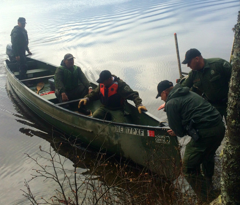 Game wardens pull a canoe ashore with Mike Jones, who spent the night in a remote camp on Grand Lake Seboeis.