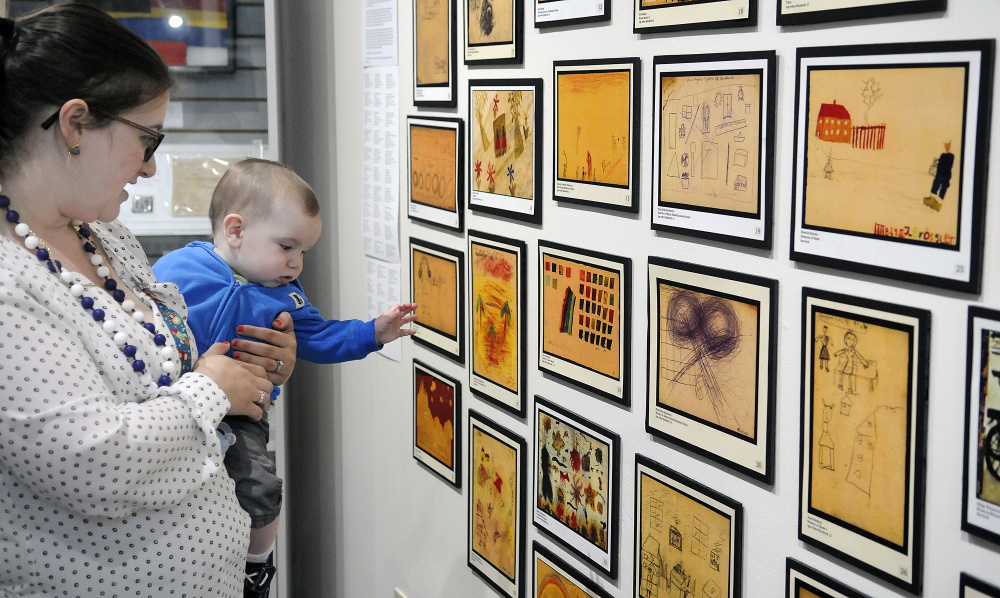 Danna Hayes and her son, Eli, seven months old, examine art on Monday that was created by children during the Holocaust at the exhibit "Those People ... Well, They're Not People at All: Children's Reactions to the Holocaust," displayed in the Holocaust and Human Rights Center of Maine in Augusta. The elder Hayes, of Bath, is the granddaughter of Holocaust survivors.