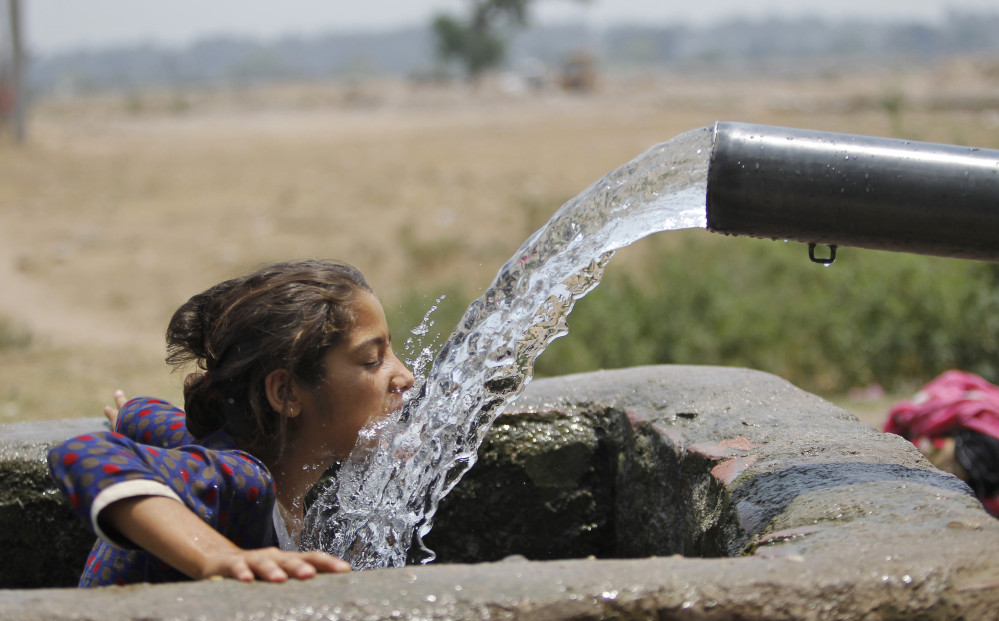 Water from an irrigation tube provides relief to a girl on the outskirts of Jammu, India, on Saturday.