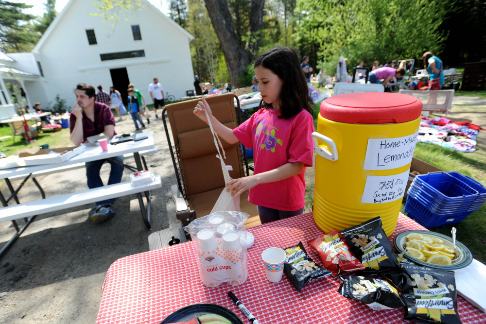 Carly McCabe, 10, sells freshly made lemonade Saturday at the annual 10-mile-long yard sale in Cornville.