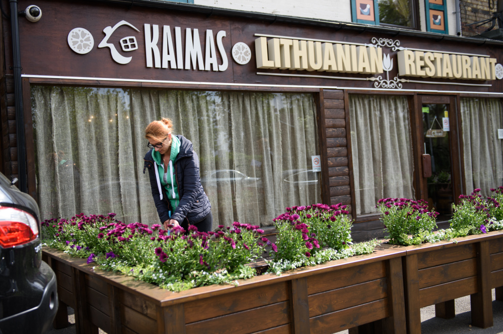 Simona Budvyte, 27, sweeps the patio of Kaimas before setting up for lunch in Peterborough, England, recently.
