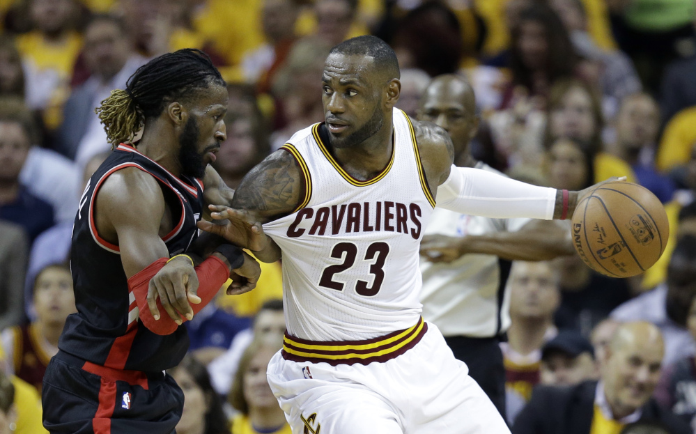 LeBron James of the Cavaliers looks to pass around Toronto's DeMarre Carroll in the first half Wednesday at Cleveland.