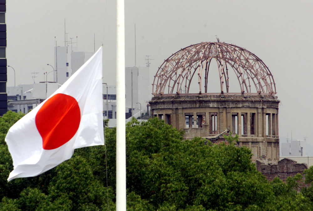 The Japanese national flag flutters at half-staff in the foreground of the atomic bomb dome at the Hiroshima Peace Memorial Park in western Japan.