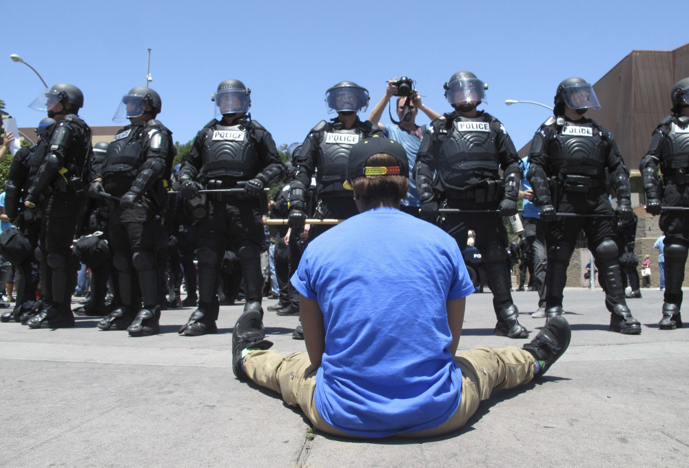 A woman sitting in the street faces riot police after a campaign rally for Republican presidential candidate Donald Trump in Fresno, Calif., on Friday. The crowd beat drums, chanted anti-Trump slogans and marched around the arena in downtown Fresno.