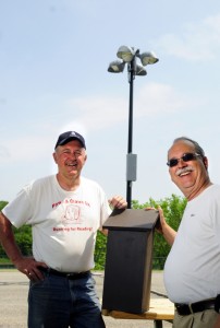 Augusta City Councilor Pat Paradis, left, poses with Ray Fecteau and a bat house at the Mill Park pétanque courts in Augusta. Fecteau said he hopes the bats will devour bugs attracted to the lights at the court during evening play.