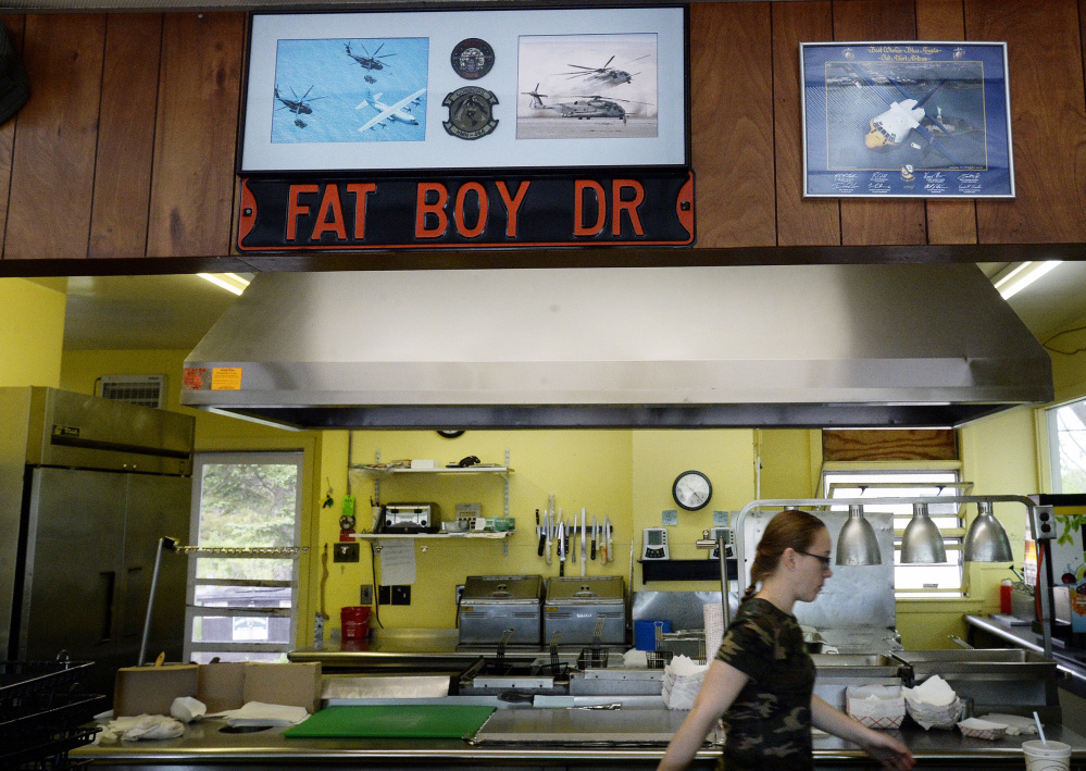 Jay Spaltrow, a car hop at Fat Boy Drive In in Brunswick, walks through the kitchen where photographs of planes on the wall are a reminder of the Brunswick Naval Air Station, which was shut down five years ago.
