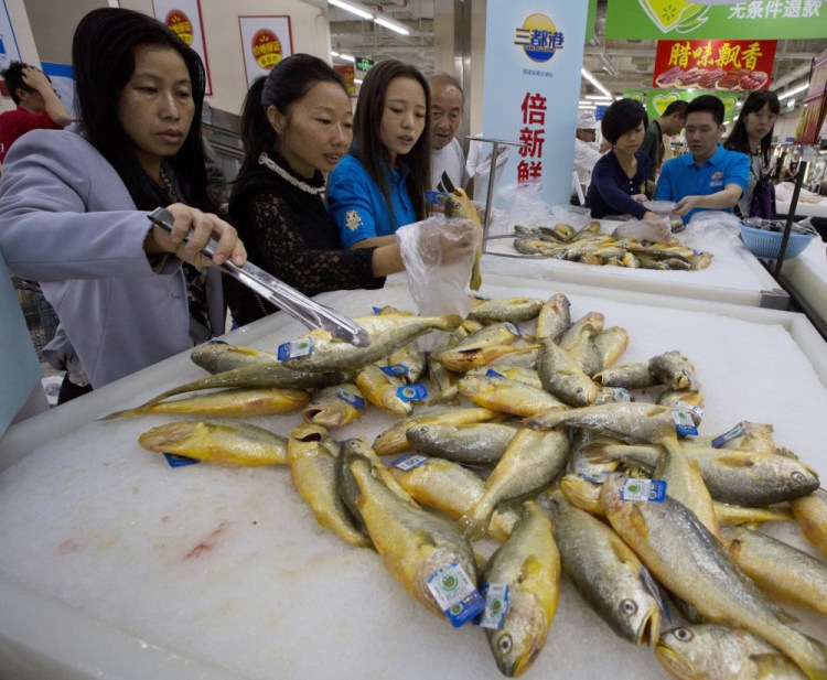 Shoppers examine fish on sale at a Wal-Mart in Shenzhen, China. Getting the food business right in China is critical to Wal-Mart's growth plans, and that's made more challenging by consumers who are renowned for their mistrust of goods providers.