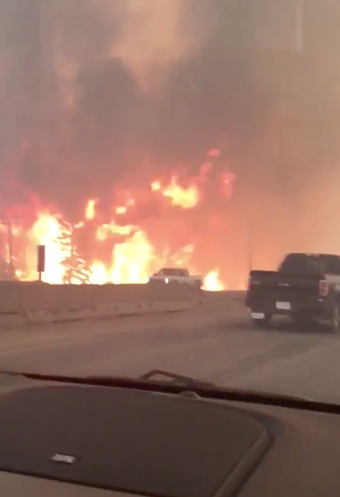 This photo provided by Tyler Burgett shows flames from a wildfire along Highway 63 in Fort McMurray, Alberta, Tuesday.
