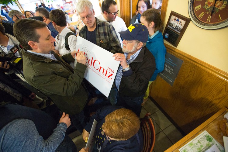 Ted Cruz, left, signs a campaign sign for a supporter inside the Bravo Cafe in Osceola, Ind. Monday, The Associated Press/Sam Householder/The Elkhart Truth