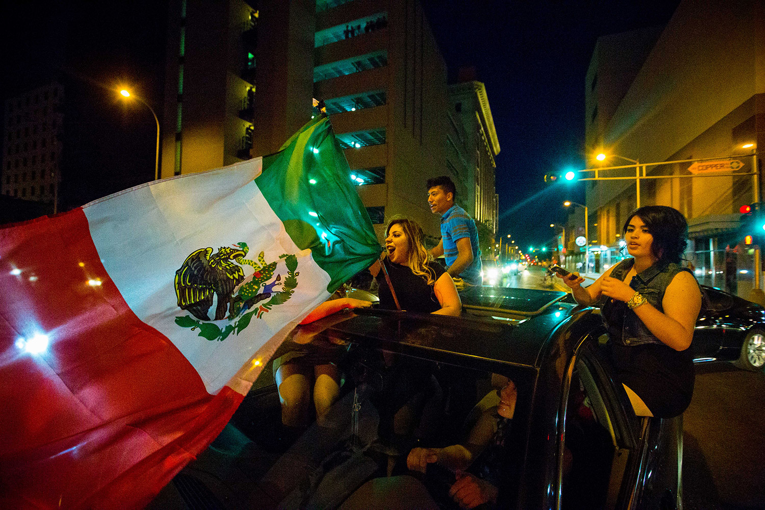 A woman waves the Mexican flag while driving past the Albuquerque Convention Center after a rally by Republican presidential candidate Donald Trump.