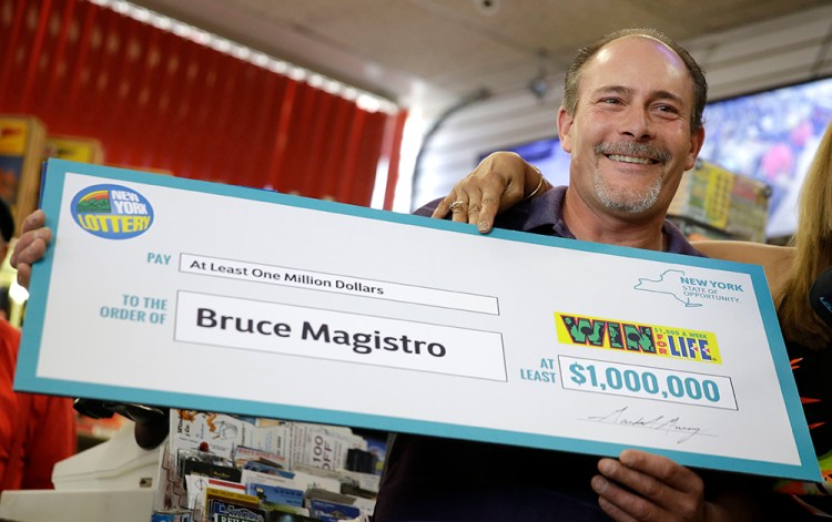 Bruce Magistro holds up a facsimile check while talking to reporters about winning $1 million in the New York Lottery for a second time. The Associated Press