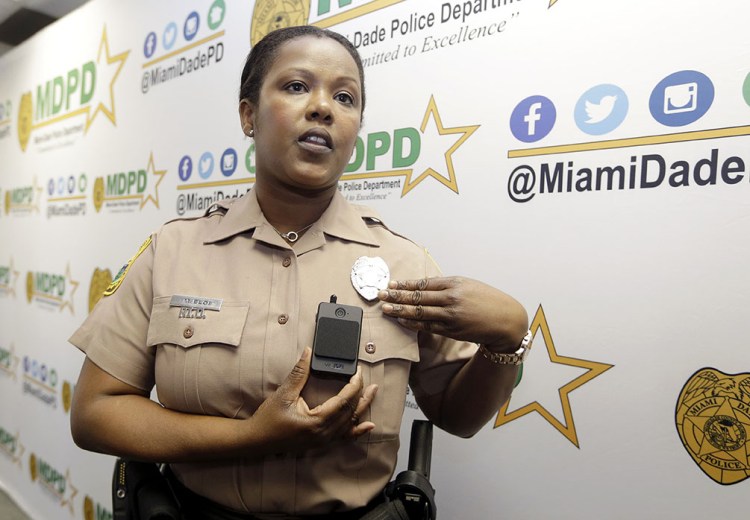 Marjorie Eloi, public information officer for the Miami-Dade Police Department, shows how to turn on a body camera, which the department will assign to about 1,000 officers in the next few months. The Associated Press