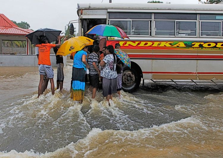 Sri Lankan flood victims flock around a bus to receive food parcels on an inundated road in Colombo on Tuesday. The Disaster Management Center said 114 homes have been destroyed and more than 137,000 people have been evacuated to safe locations as heavy rains continue. The Associated Press