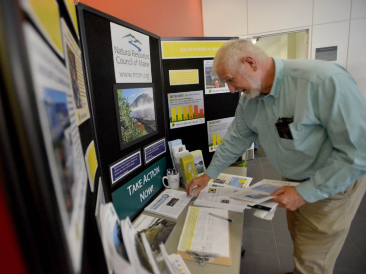 David Woodsome, state senator from Sanford, picks up pieces of solar power literature before speaking Thursday at The Future of Solar in Maine Forum at Colby College in Waterville.