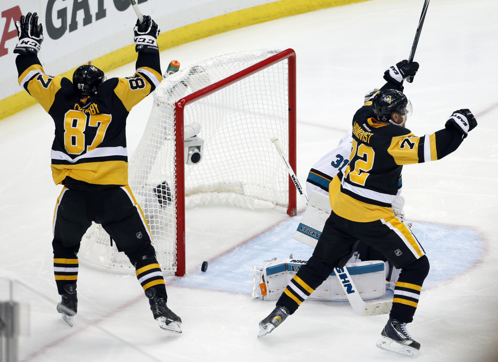 Sidney Crosby and Patric Hornqvist, right, of the Penguins celebrate a goal by Conor Sheary against Sharks goalie Martin Jones in overtime in Game 2 of the Stanley Cup Final Wednesday in Pittsburgh. The Penguins won 2-1 to take a 2-0 lead in the series.