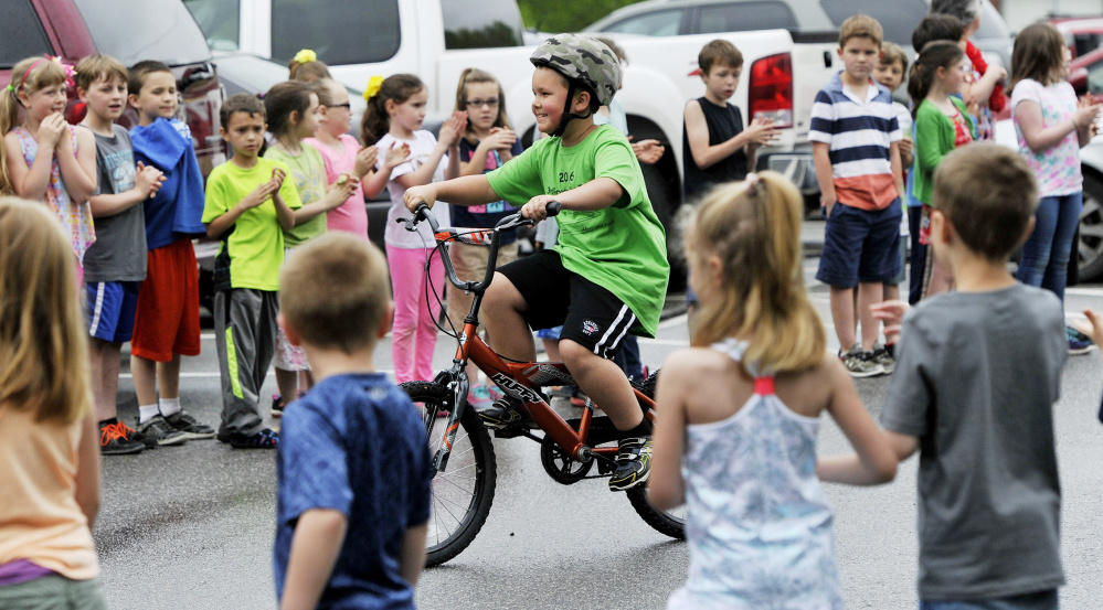 Nathan Lewis rides between lines of cheering students as he and his schoolmates  embark on the annual third-grade beach bike ride.