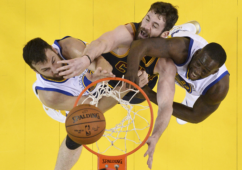Cleveland forward Kevin Love, center, reaches for the ball between Golden State center Andrew Bogut, left, and forward Draymond Green in the first half of Thursday night's game in Oakland.