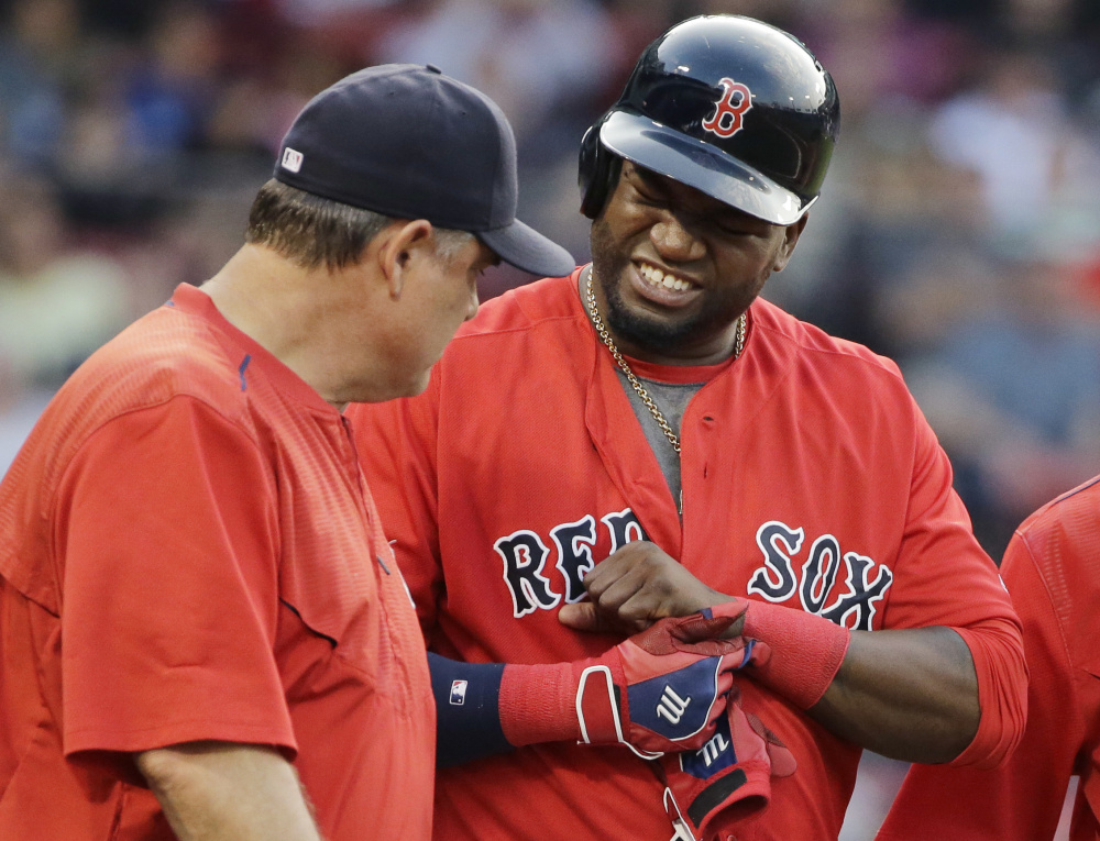 Red Sox designated hitter David Ortiz grimaces while showing Red Sox Manager John Farrell where he got hit by a pitch in the first inning.