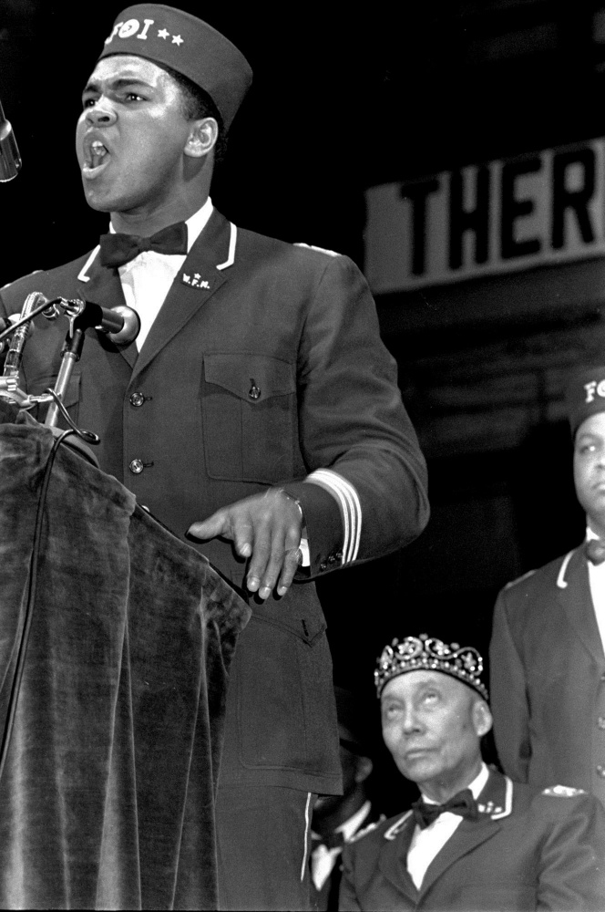 Former heavyweight boxing champion Muhammad Ali speaks at a Black Muslim convention in Chicago on  Feb. 25, 1968.  Seated behind Ali is Elijah Muhammad, leader of the Nation of Islam. (AP Photo/file)