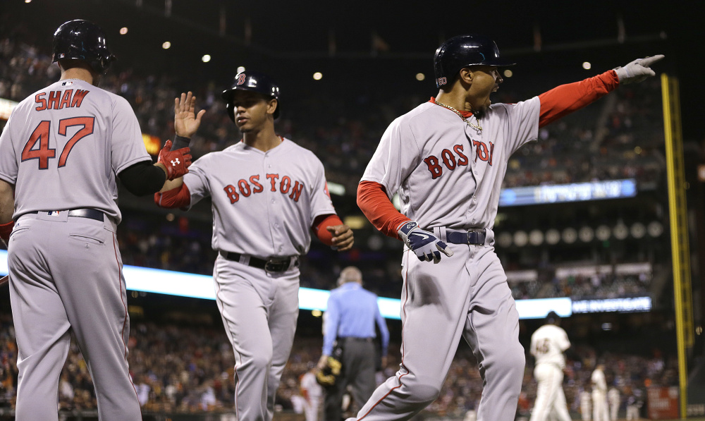 Mookie Betts, right, and Marco Hernandez, center, run past Travis Shaw after scoring on Xander Bogaerts' bases-loaded single in the 10th inning Tuesday night in San Francisco.
