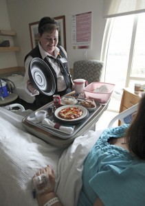Beth Loney, a service assistant at Mercy Hospital, serves lunch to a patient.