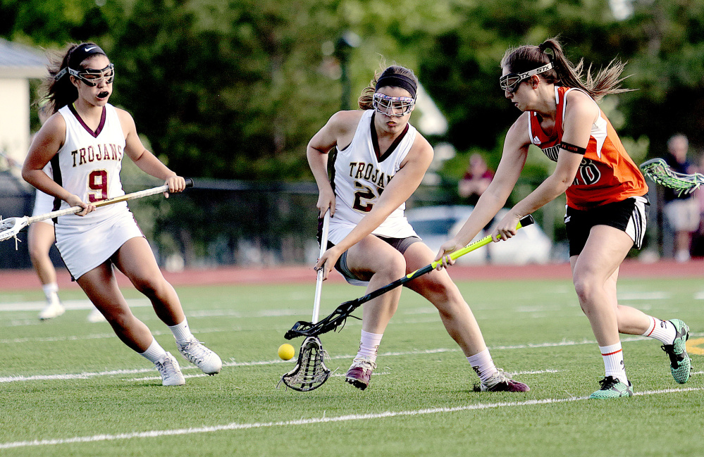 Addy Paradis, left, of Thornton Academy, looks on as teammate Rachel Richard, center, fights for the ball with Biddeford's Taylor Turgen during a Class A South girls lacrosse quarterfinal on Wednesday in Saco. Thornton won the game, 15-1.