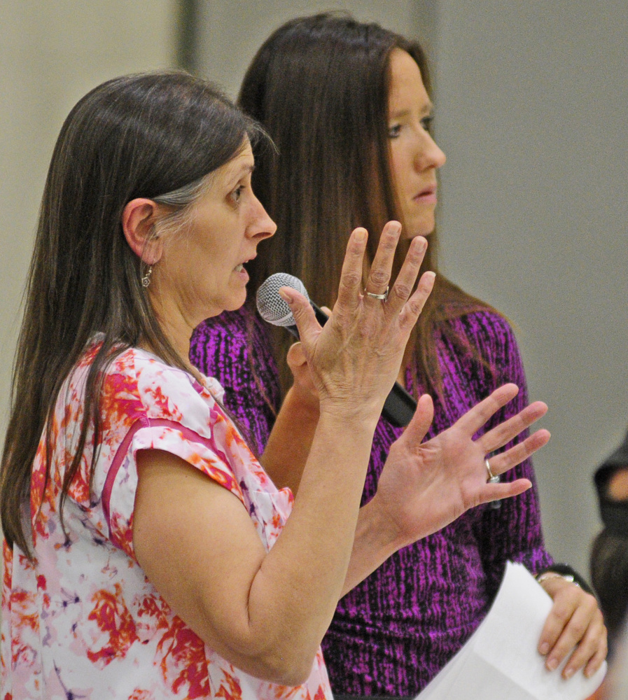 Linda Deforge of Augusta, left, asks a question as LePage press secretary Adrienne Bennett holds the microphone during Wednesday's town hall meeting at the Augusta Armory.