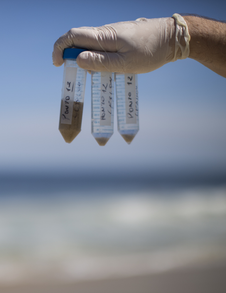 A researcher shows water and sand samples he collected in the water off Rio de Janeiro for a study commissioned by The Associated Press in March.
