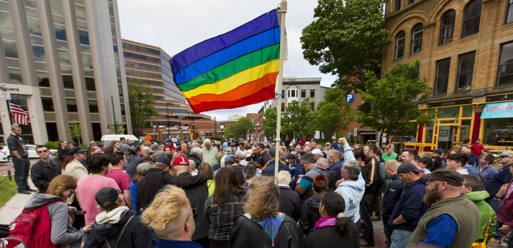 A pride flag flies over Sunday's vigil in Monument Square to remember victims of the mass shooting in Orlando.