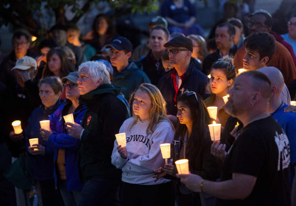 Part of the large crowd listens to speakers Monday during a candlelight vigil outside Portland City Hall, one of numerous vigils held around the state.