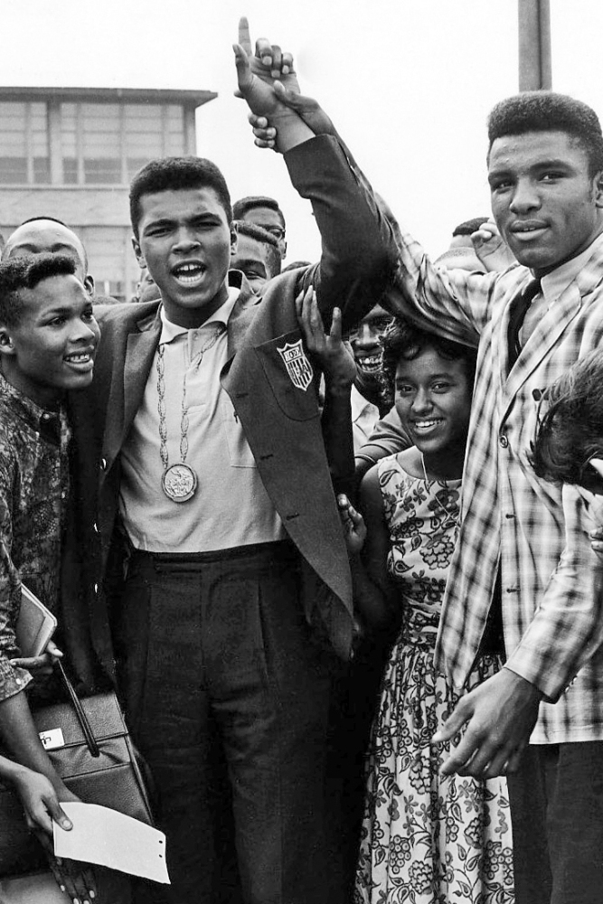 Cheering students of Central High School surround Olympic boxing champion Cassius Clay, wearing Olympic gold medal, in Louisville, Ky., in 1960.